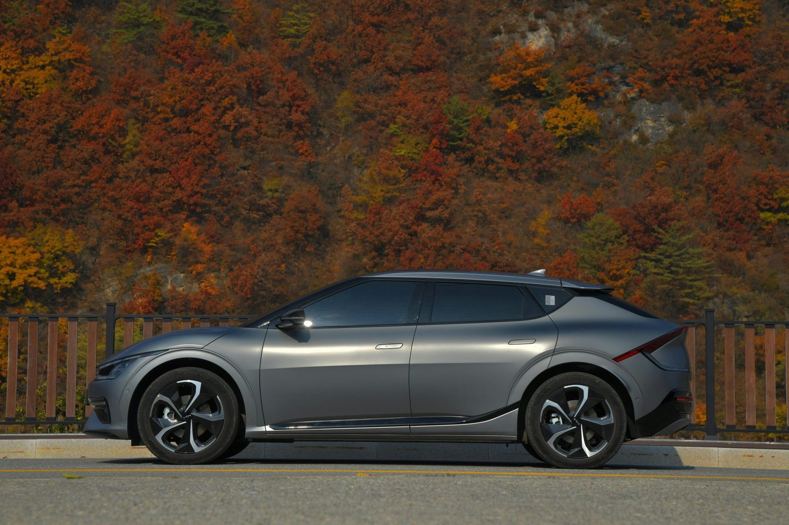 a silver car parked on the side of a road with trees in the background